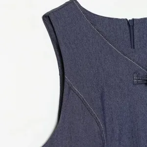 Gedetailleerd overzicht van mouwloze denim damesjurk met contraststiksels en knoppen.