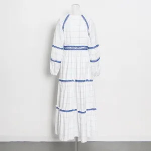 Vista detallada del elegante vestido blanco de manga larga con cuadros azules y encaje.