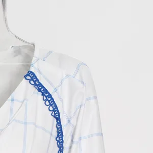Detalle en primer plano del vestido a cuadros blanco y azul con delicado ribete de encaje azul.
