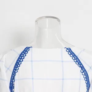 Primer plano detallado de una blusa a cuadros blancos con elegante ribete de encaje azul en hombros.