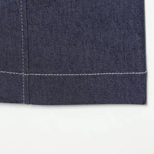 Detailopname van donkerblauwe denimstof met strakke witte stiksels en nette naadafwerking.