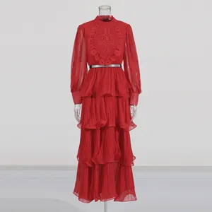 Robe longue rouge à manches longues et volants, broderie délicate sur le buste et fine ceinture.