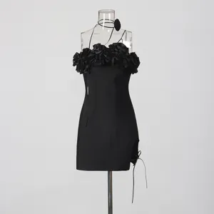 Detalle de vestido corto negro con volantes florales en 3D y abertura lateral chic.