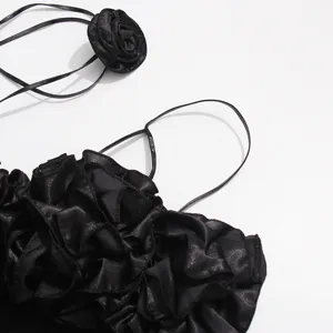 Vista detallada del vestido negro con roseta 3D, tela satinada con elegante tirante halter.