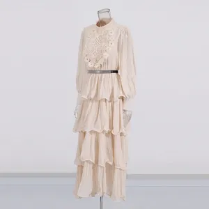 Robe longue beige vintage à manches longues et volants avec broderie et jolie ceinture.
