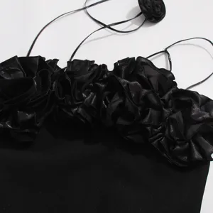 Vista detallada del vestido negro con volantes florales en 3D y tirantes finos muy elegantes.