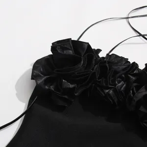 Detalle de vestido lencero negro halter con diseño floral de roseta 3D elegante.