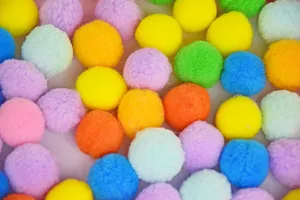 Colorful fluffy pom poms close up detail view for fun DIY crafts and cute pet toys