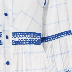 Primer plano del detalle del vestido de cuadros de manga larga con ribete de encaje azul.