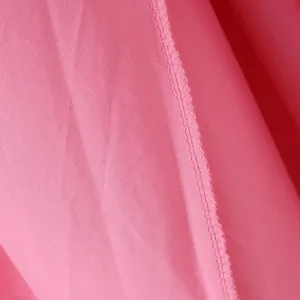 Rosa Stoff Detailansicht zeigt saubere Overlock Naht und glatte Textur für das schöne Kleid.