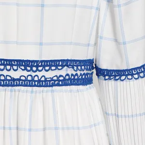 Detalle de un vestido largo a cuadros blancos y azules con ribete de encaje azul.