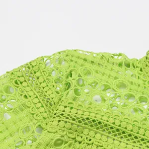 Gros plan sur le tissu en dentelle vert vif montrant des motifs au crochet et details floraux.