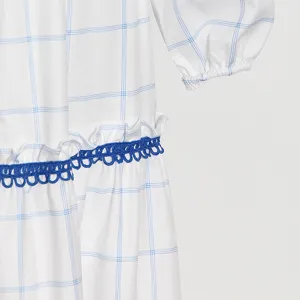 Detalle del vestido de cuadros con patrón de cuadrícula azul y delicados adornos de encaje.