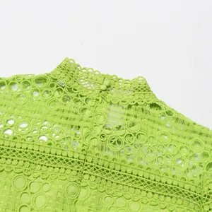 Gros plan sur les détails de la robe verte en dentelle brodée ajourée à col montant, motif floral.