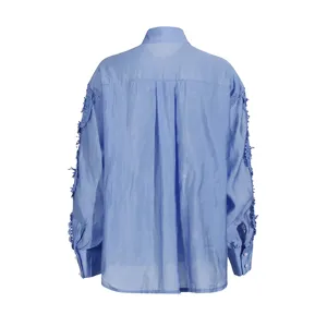Detalle camisa manga larga azul, vista trasera con bordado de encaje y botones.