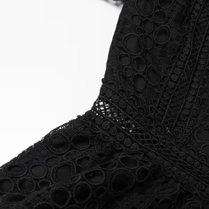 Détail de tissu en dentelle géométrique ajourée lourde noire de robe élégante de mode.