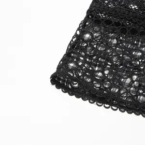 Vue détaillée de tissu en dentelle crochetée noire, ourlet à motif floral pour robes élégantes.