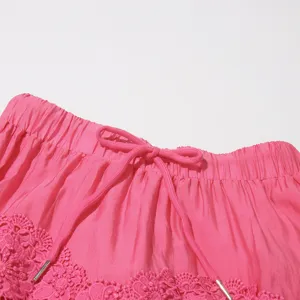 Primer plano detalle falda rosa con cordon ajustable y dobladillo encaje floral.