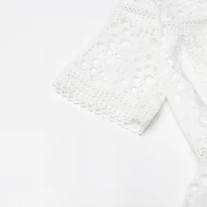 Vue détaillée de la manche courte en dentelle blanche, texture de broderie au crochet élégante.