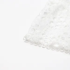 Gros plan sur un tissu de dentelle blanche, avec une délicate broderie florale ajourée.
