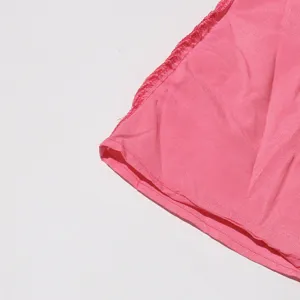 Detalle del dobladillo rosa de la falda con costuras finas y textura de tela suave.