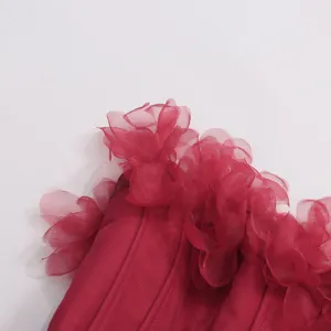 Détail en gros plan de la robe rouge sans bretelles avec des fleurs en organza et un corset.
