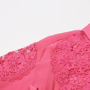 Primer plano de una camisa rosa de verano con bordado de encaje intrincado y detalles calados.