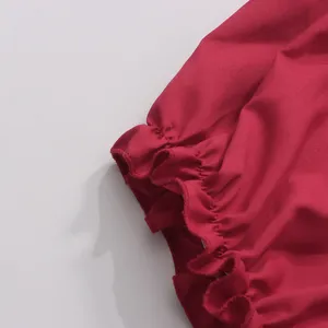 Gros plan détaillé de la manche à volants froncés rouge vif avec une belle texture fine.