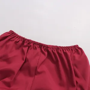 Détail de robe rouge en gros plan montrant l'encolure froncée élastique et belle texture.