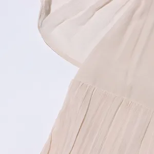 Vue détaillée de femme élégante robe plissée beige texture de tissu à volants été