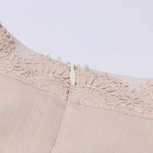 Détail de robe en dentelle beige, fermeture invisible et broderie exquise gros plan.