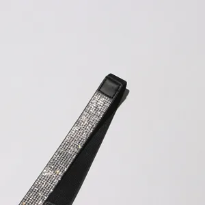 Gros plan détaillé de la ceinture élastique scintillante en strass avec bande noire élégante.