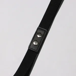 Gros plan sur le détail de la ceinture de robe noire avec sangle élastique et boutons.