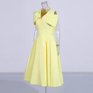 Close-up detail of the elegant yellow midi dress featuring a stylish large shoulder bow.