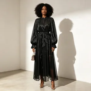 Détail de robe longue noire transparente à manches longues, tissu brillant et ceinture nouée.