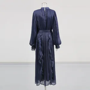 Vue détaillée de la robe longue bleu foncé à manches longues en tissu brillant avec volants.