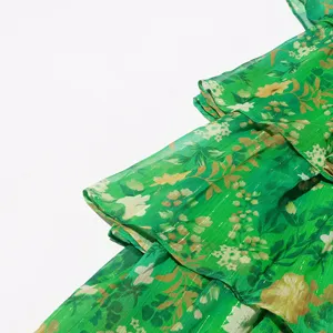 Detalle de vestido de gasa floral verde con volantes en capas y tela brillante.