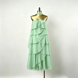 Détail de robe longue sans bretelles en mousseline vert menthe, volants étagés et ruban élégant.