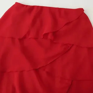 Gros plan détaillé de la robe rouge en mousseline à volants, montrant un tissu élégant.