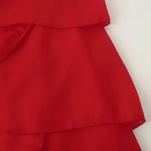 Détail de robe en mousseline rouge montrant la texture superposée et le tissu fluide.