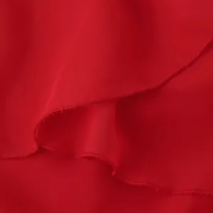 Gros-plan détail tissu mousseline rouge robe femme texture volants plissés délicats.