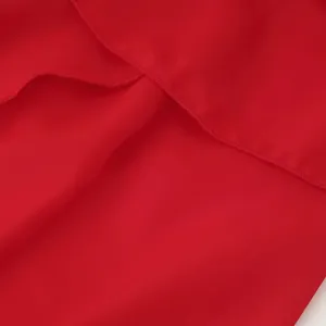 Détail de la robe en mousseline rouge avec des volants superposés et une texture douce.