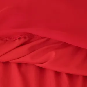 Gros plan sur le tissu de robe en mousseline rouge avec coutures délicates et texture.