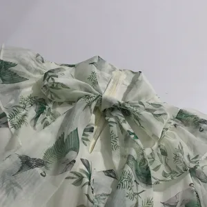 Close-up of women's floral bird print dress neckline with ruffles and tie bow detail.