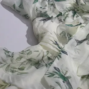 Close-up detail of green bird floral print long sleeve dress with ruffles and pleats.