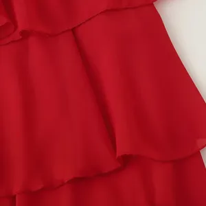 Gros plan sur le tissu en mousseline rouge avec volants superposés et texture élégante.