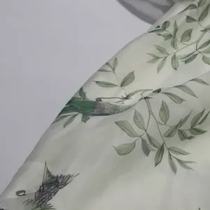 Detailed close-up of light green fabric featuring vintage bird and botanical leaf print.