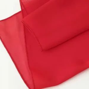Gros plan détaillé d'une texture de tissu mousseline rouge vif avec des bords roulés.