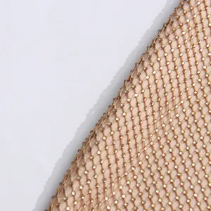 Gros plan sur les détails du tissu en maille de strass et sequins dorés pour robe élégante.