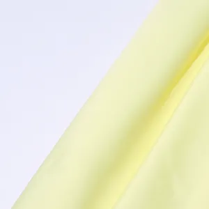 Close-up detail of light yellow fabric texture, soft drape and smooth surface for elegant dress.
